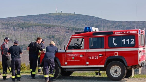 Einsatzkräfte der Feuerwehr beobachten vom niedersächsischen Wurmberg aus das Waldbrandgebiet am Brocken. © dpa-Bildfunk Foto: Matthias Bein/dpa