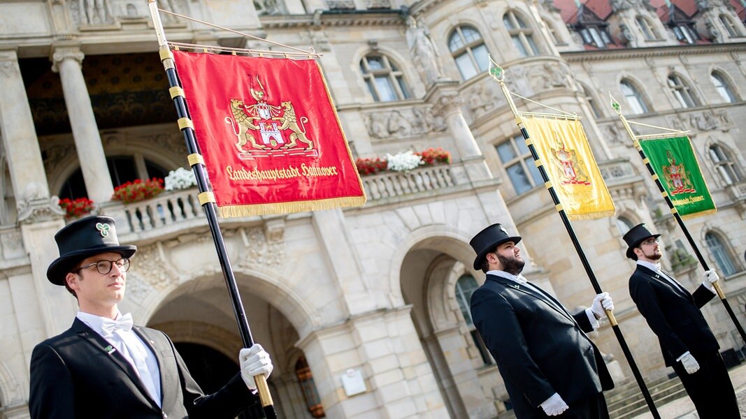 Vier Bruchmeister stehen mit ihren Standarten vor dem symbolischen Fassanstich zum Schützenfest vor dem Neuen Rathaus. 