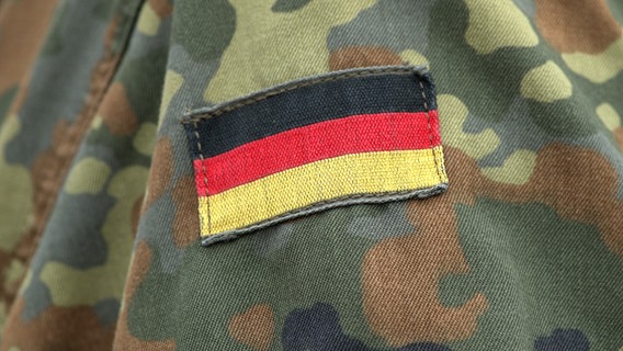 Der Aufnäher einer Deutschlandflagge auf dem Camouflage-Hemd eines Soldaten der Bundeswehr. © picture alliance/SULUPRESS.DE Foto: Torsten Sukrow