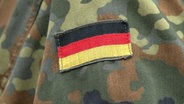 Der Aufnäher einer Deutschlandflagge auf dem Camouflage-Hemd eines Soldaten der Bundeswehr. © picture alliance/SULUPRESS.DE Foto: Torsten Sukrow