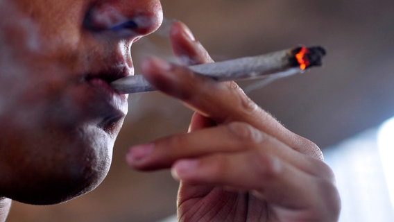 Eine Person zieht an einem joint. © picture alliance / ZUMAPRESS.com | Cris Faga Foto: Cris Faga