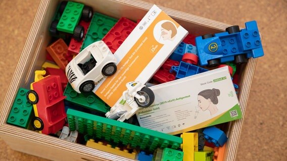 Corona-Selbsttests verschiedener Hersteller liegen in einer Spielzeugkiste in einer Kindertagesstätte. © dpa-Bildfunk Foto: Friso Gentsch