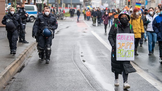 Eine Teilnehmerin einer Demonstration gegen die Corona-Maßnahmen trägt ein Plakat mit der Aufschrift "Gegen Impfpflicht" um den Hals. © dpa Foto: Lino Mirgeler