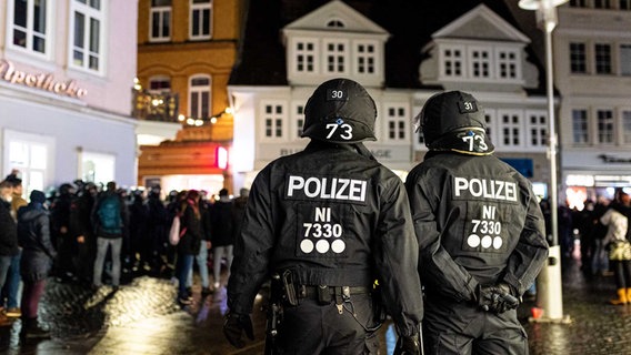 Behelmte Einsatzkräfte der Polizei stehen am Abend bei einem «Spaziergang» von Gegnern der Corona-Politik in der Innenstadt in Braunschweig. © picture alliance/dpa Foto: Moritz Frankenberg