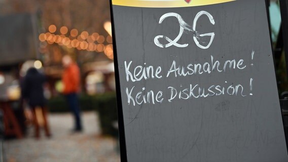 "2G Keine Ausnahme! Keine Diskussion!" steht auf dem Schild an einem Zugang zum einem Weihnachtsmarkt. © dpa Foto: Martin Schutt