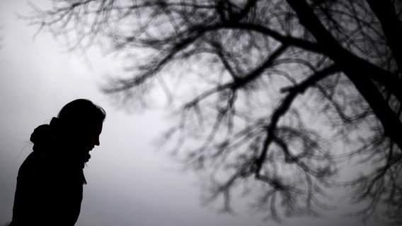 Eine Frau steht bei grauem Himmel neben einem Baum. © picture alliance/dpa | Julian Stratenschulte Foto: Julian Stratenschulte