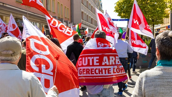 Teilnehmer eines Demonstrationszuges laufen mit Fahnen des DGB durch eine Innenstadt. © picture alliance/dpa | Frank Hammerschmidt Foto: Frank Hammerschmidt