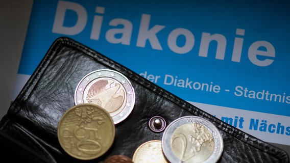 Ein Portemonnaie mit Geldmünzen liegt auf einer Broschüre der Diakonie. © picture alliance / dpa | Arno Burgi Foto: Arno Burgi