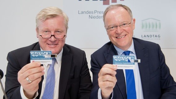 Bernd Althusmann (CDU, l), Wirtschaftsminister Niedersachsen, und Stephan Weil (SPD), Ministerpräsident Niedersachsen, stellen im Landtag den Masterplan Digitalisierung vor - und zeigen eine Karte mit eingebauten USB-Stick. © Julian Stratenschulte/dpa Foto: Julian Stratenschulte