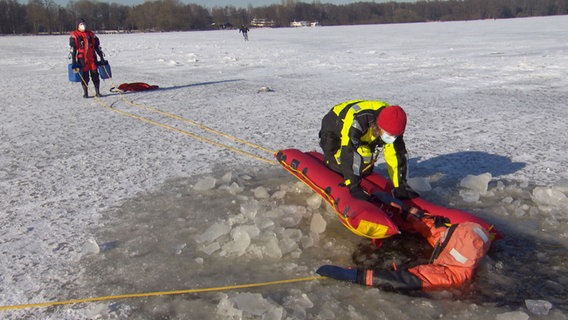 Ein in einen zugefrorenen See eingebrochener Mensch wird bei einer Übung der DLRG aus dem See gezogen. © NDR 