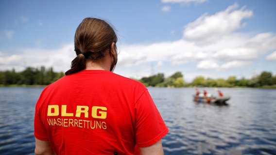 Ein Rettungsschwimer der DLRG blickt auf eine Übung auf dem Wasser. © picture alliance/Geisler-Fotopress Foto: Christoph Hardt