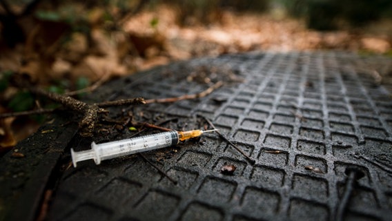 Eine benutzte Spritze nach Drogenkonsum liegt im Gebüsch nahe eines U-Bahnhofes. © dpa-Bildfunk 