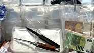 Sichergestellt: Geld, Waffen und Drogen liegen auf einem Tisch. © Polizei Osnabrück Foto: Polizei Osnabrück