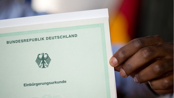 Ein Mann zeigt bei einer Einbürgerungszeremonie seine Einbürgerungsurkunde der Bundesrepublik Deutschland. © picture alliance / Julian Stratenschulte / dpa | Julian Stratenschulte Foto: Julian Stratenschulte