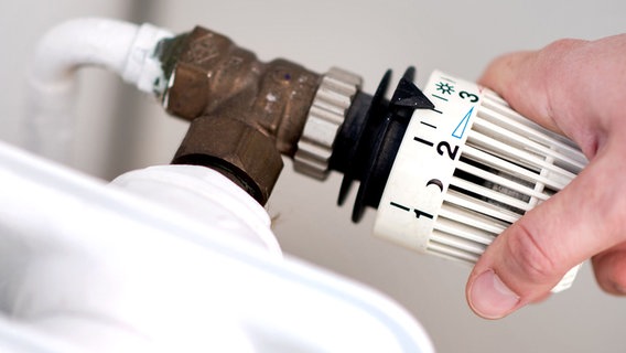 Eine Hand am Thermostat einer Heizung. © Hauke-Christian Dittrich/dpa Foto: Hauke-Christian Dittrich/dpa