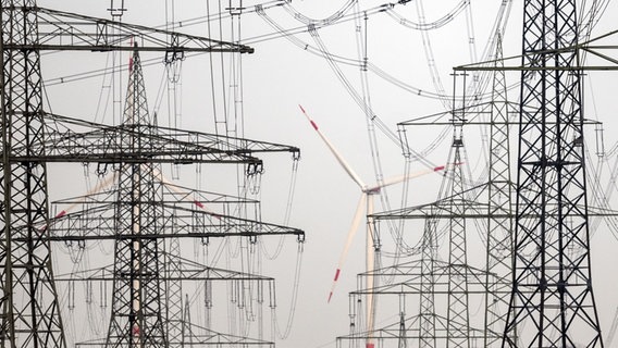 Hinter vielen Strommasten drehen sich Windräder, die Strom erzeugen. © dpa Foto: Federico Gambarini