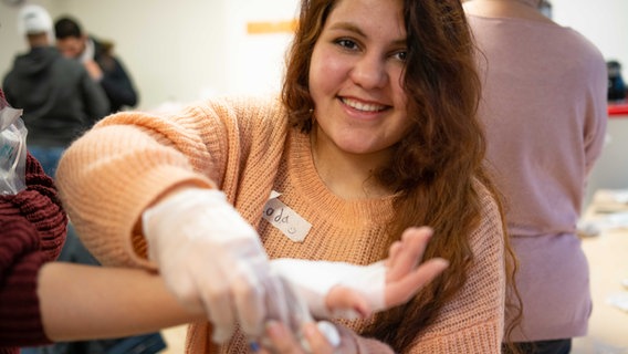 Eine junge Frau übt, einen Verband anzulegen. © Anette Thanheiser/Johanniter Foto: Anette Thanheiser