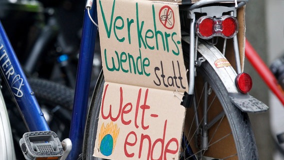 Fahrradaktivisten und Klimaschützer haben eine Pappe mit dem  "Verkehrswende statt Weltende" an ein Fahrrad montiert. © picture alliance/dpa Foto: Roland Weihrauch