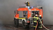 Ein Einsatzfahrzeug der Feuerwehr steht in dicken Rauchschwaden. © NDR Foto: Stefan Rampfel