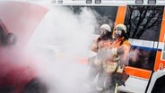 Zwei Feuerwehrleute mit Atemschutzmasken löschen einen Brand. © NDR Foto: Julius Matuschik