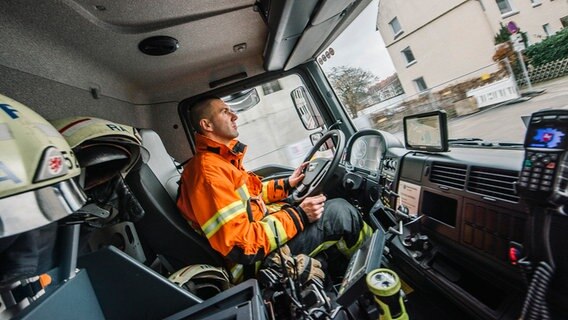 Ein Feuerwehrmann sitzt am Steuer eines Feuerwehrautos. Ein Feuerwehrmann sitzt am Steuer eines Feuerwehrautos. © NDR Foto: Julius Matuschik