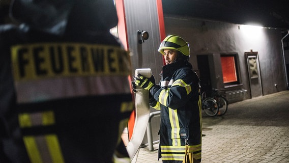 Ein Feuerwehrmann hält einen Wasserschlauch in der Hand. © NDR Foto: Julius Matuschik