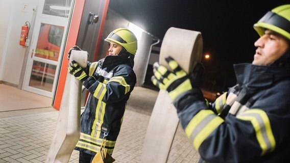 Zwei Feuerwehrleute halten einen Wasserschlauch in der Hand. © NDR Foto: Julius Matuschik