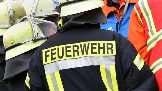 Der Schriftzug Feuerwehr steht auf einer Jacke einer Einsatzkraft. © dpa - picture alliance Foto: Holger Hollemann