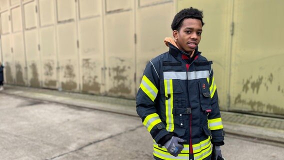 Godswill Ihama, 18, aus Frankreich, seit zwei Jahren in Deutschland, trägt eine Feuerwehr-Uniform. © NDR Foto: Catherine Grim