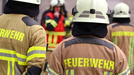 Auf dem Rücken zweier Einsatzkräfte steht "Feuerwehr". © dpa - picture alliance Foto: Tino Plunert