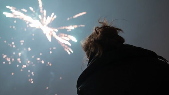 Eine Frau blickt auf ein Feuerwerk. © picture alliance / dpa Themendienst Foto: Florian Schuh