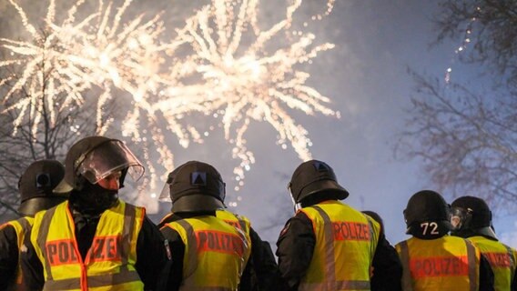 Polizisten sind im Einsatz. Im Hintergrund ist ein Feuerwerk zu sehen. © dpa-Bildfunk Foto: Clemens Heidrich