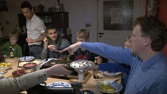 Die Brüder Abd sitzen am Silvesterabend mit Familie Berndt beim Abendessen zusammen. © NDR 