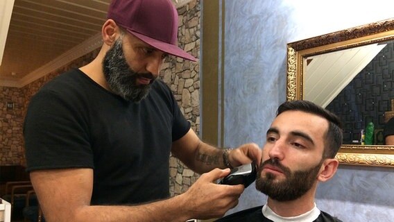 Ein Mann rasiert einem anderen Mann den Bart. © NDR Foto: Silke Rudolph