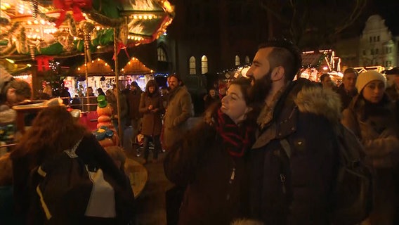Basel Taifour geht mit seiner Verlobten Katharina über einen Weihnachtsmarkt. © NDR 