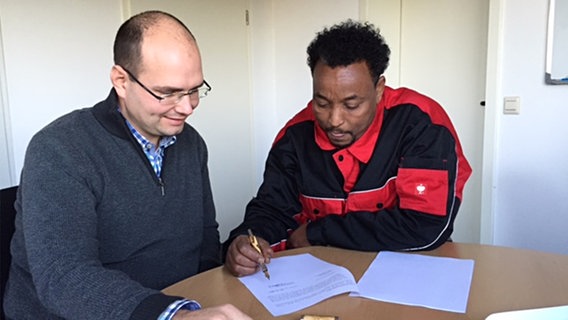Hamsa Mahamed Hassan unterschreibt einen Arbeitsvertrag. © NDR 