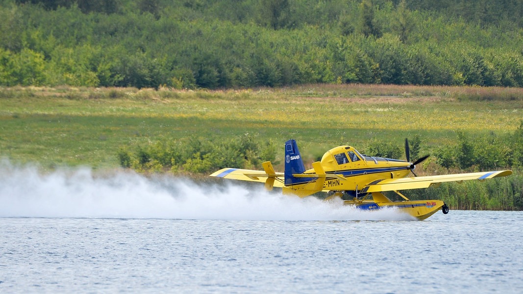 Ein Löschflugzeug des Typs AT 802 nimmt Wasser aus einem See auf.