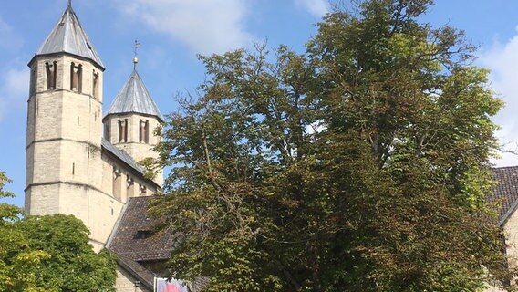 Eine Kirche mit zwei Glockentürmen, davor ein großer Baum. © Stadt Bad Gandersheim 