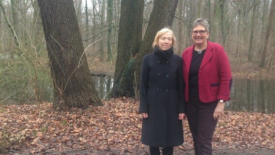 Zwei Frauen stehen vor einem Baum, im Hintergrund ist ein Teichzu sehen. © NDR Foto: Andrea Heußinger