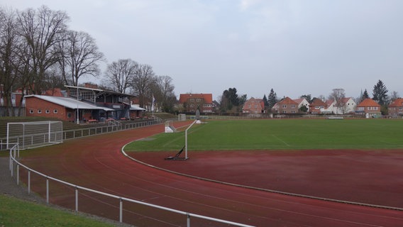 Ein Sportplatz. Um den Rasen führt eine rote Laufbahn, rechts eine Zuschauertribüne und ein kleines Gebäude. © NDR Foto: Andrea Heußinger
