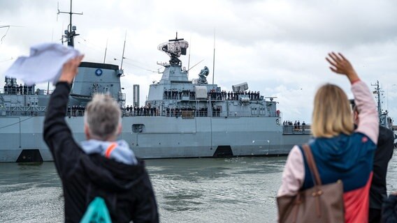 Angehörige winken, während die Fregatte "Schleswig-Holstein" aus dem Hafen fährt. © dpa Foto: Sina Schuldt