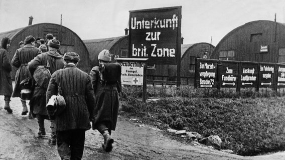 Heimkehrer gehen 1946 im Lager Friedland auf die als Notunterkünfte dienenden Nissenhütten zu. © dpa - Bildfunk Foto: dpa