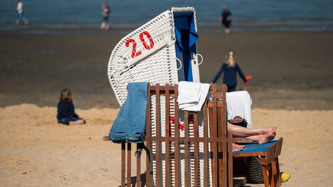 Menschen und ein Strandkorb am Strand von Cuxhaven bei sonnigen Wetter
