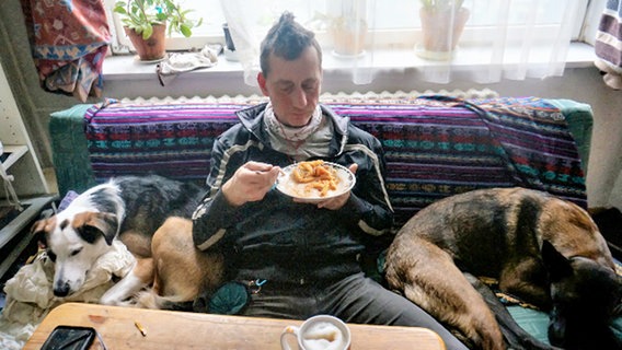 Der Ex-RAF-Terrorist Burkhard Garweg sitzt zwischen zwei Hunden auf einem Sofa. © Landeskriminalamt Niedersachsen 