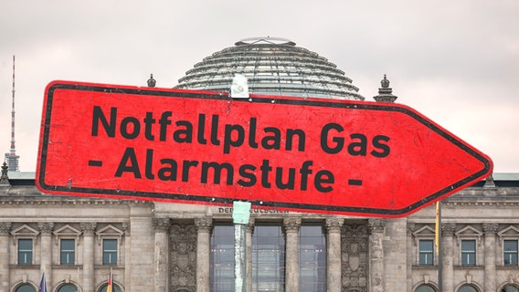 Fotomontage: Ein Schild mit "Notfallplan Gas - Alarmstufe -" vor dem Berliner Reichstagsgebäude. © picture alliance / SULUPRESS.DE | Torsten Sukrow/SULUPRESS.DE Foto: Torsten Sukrow