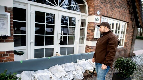 Gastronom Nico Winkelmann sichert den Eingang zum Bümmersteder Krug mit Sandsäcken, um das Restaurant vor einem drohenden Hochwasser zu schützen. © Hauke-Christian Dittrich/dpa Foto: Hauke-Christian Dittrich/dpa