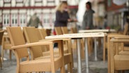 Leere Tische und Stühle stehen vor einem Café. © Picture Alliance Foto: Matthias Bein