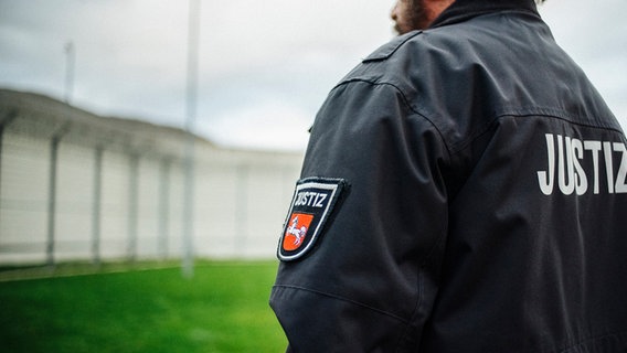 Ein Justizvollzugsbeamter steht im Innenhof eines Gefängnisses. © NDR Foto: Julius Matuschik