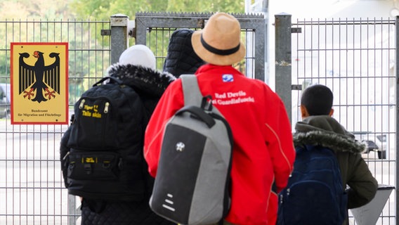 Geflüchtete betreten neben einem Schild vom Bundesamt für Migration und Flüchtlinge die Landesaufnahmebehörde Niedersachsen am Standort Braunschweig © picture alliance/dpa Foto: Julian Stratenschulte