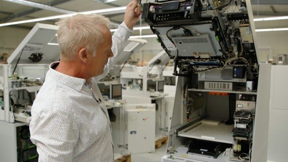 Lothar van den Berg von der Firma "SPL Computer Trading GmbH" steht an einem geöffneten Geldautomaten. © NDR 